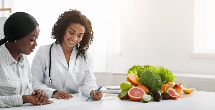 African woman nutritionist making treatment plan for female patient Cheerful african woman nutritionist making treatment plan for female patient, clinic interior